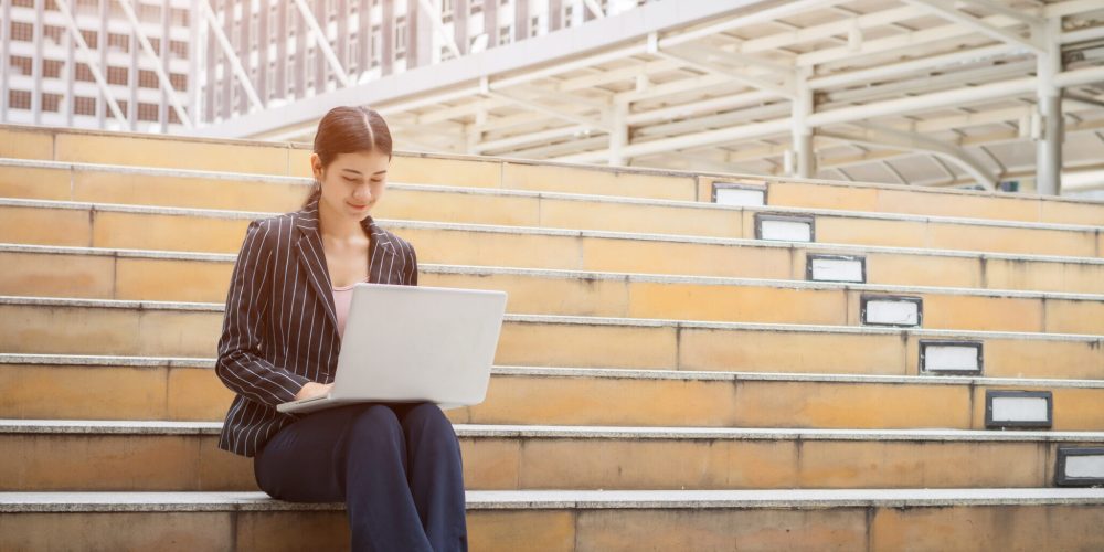Business woman using laptop sits on the steps. Business people concept.