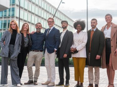 Portrait of smiling businesspeople posing for a group photo, standing outside the office showing unity and cooperation together. Company staff members in row looking at camera and laughing for corporate album. High quality photo