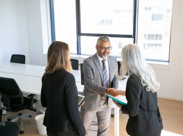 Positive confident business partners ending meeting with handshake, in office and discussing collaboration. High angle. Communication or partnership concept