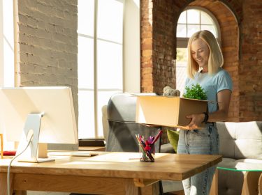 A young businesswoman moving in the office, getting new work place. Young caucasian female office worker equips new cabinet after promotion. Looks happy. Business, lifestyle, new life concept.